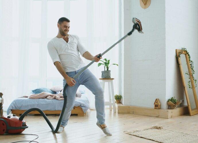 Man spielt Luftgitarre auf dem Staubsauger, mit dem er eigentlich staubsaugen wollte