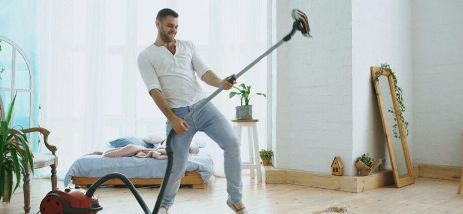 Man spielt Luftgitarre auf dem Staubsauger, mit dem er eigentlich staubsaugen wollte